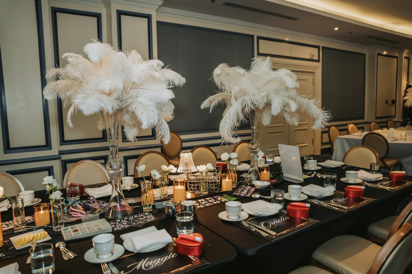 Elaborate dining table set for an elegant indoor event with feather centerpieces.